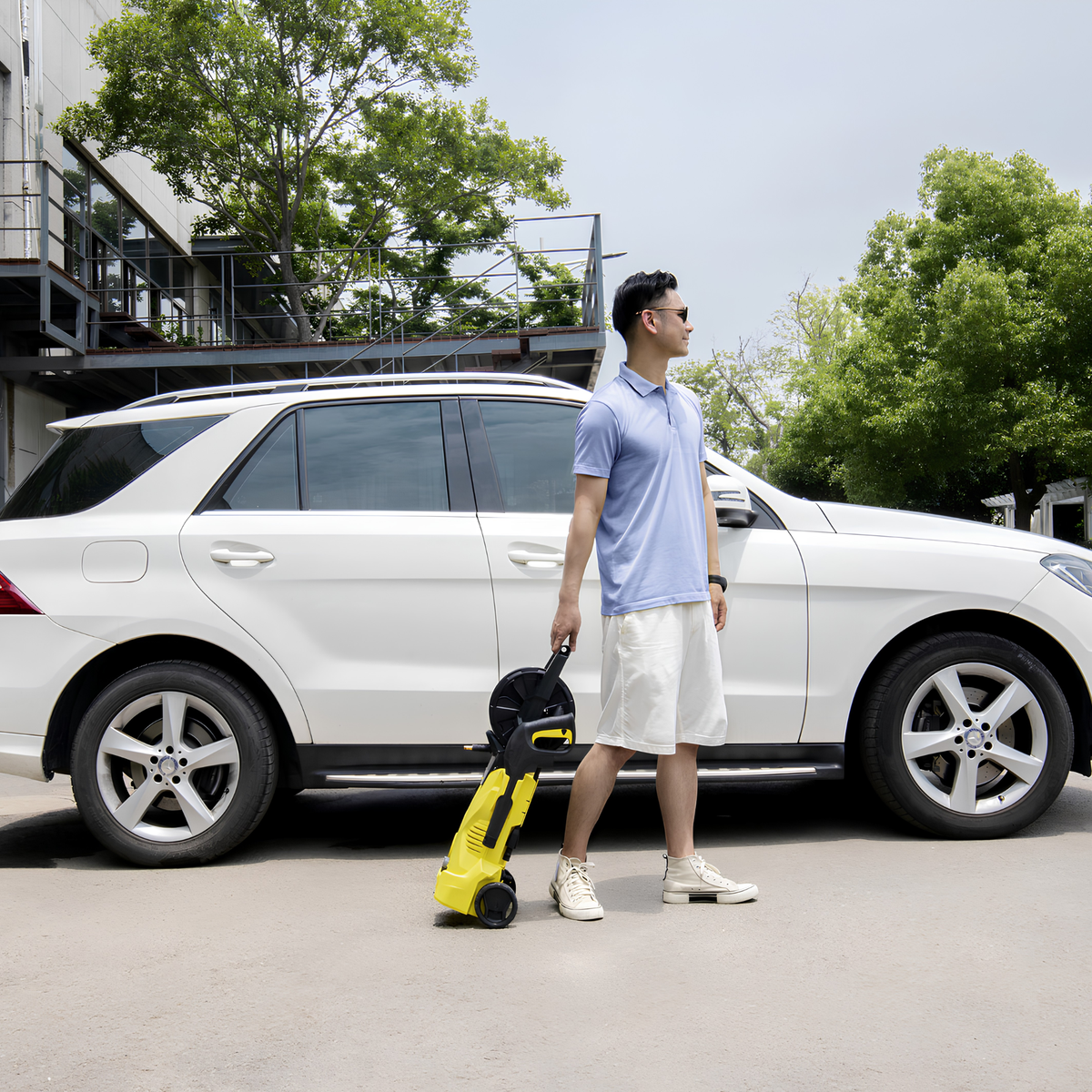 Man standing next to a white SUV holding a yellow robot-like device.