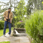 Man using a pressure washer on stone steps in a garden