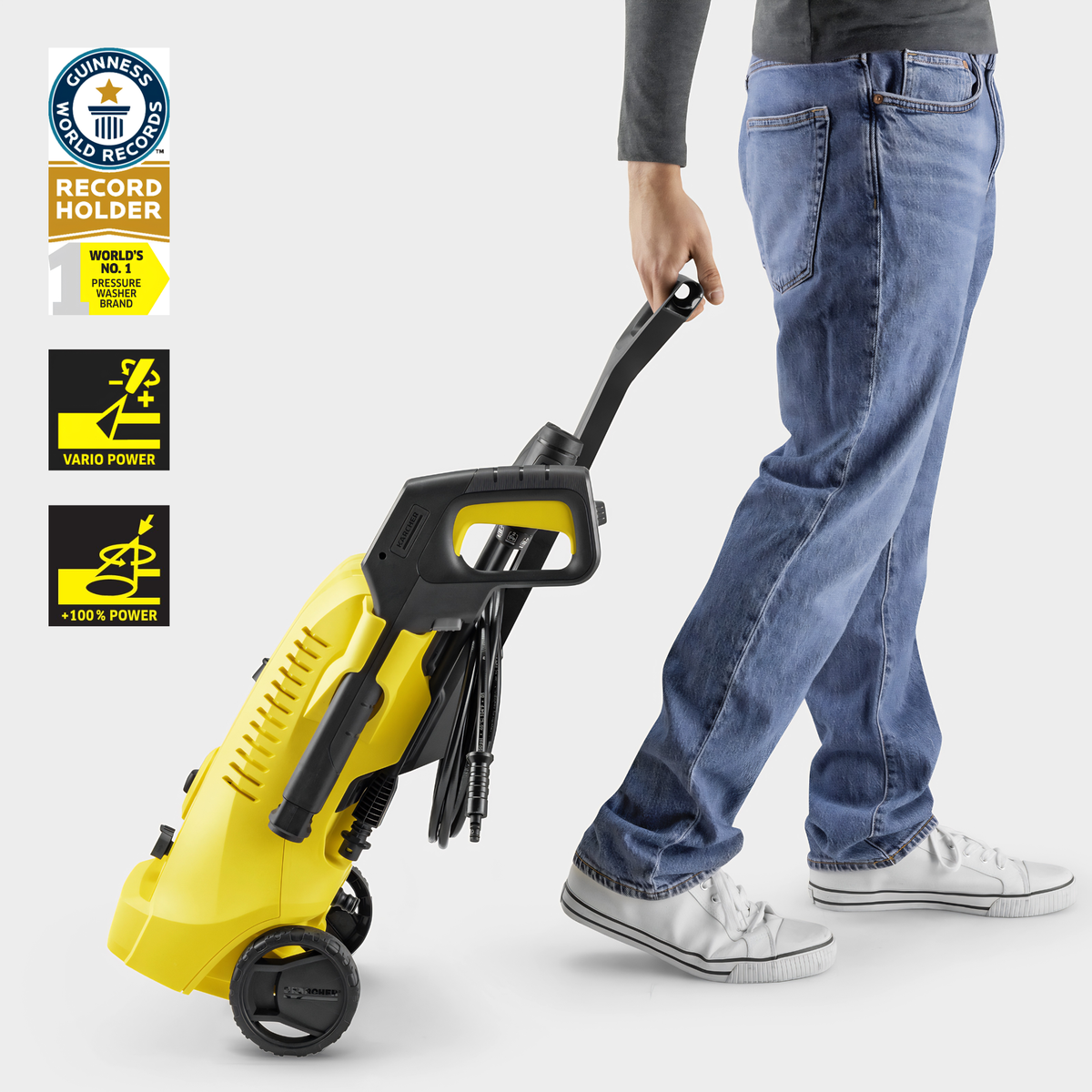 Person holding a yellow and black pressure washer with brand logos on a white background