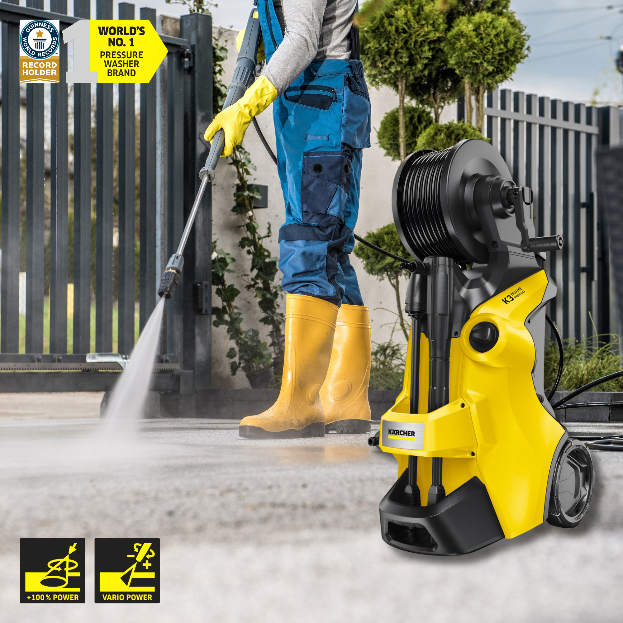 Person using a yellow pressure washer with a hose, wearing blue pants and yellow boots, in an outdoor setting.