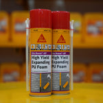 Two cans of Sika Boom AP High Yield Expanding PU Foam on a yellow surface with blurred background.