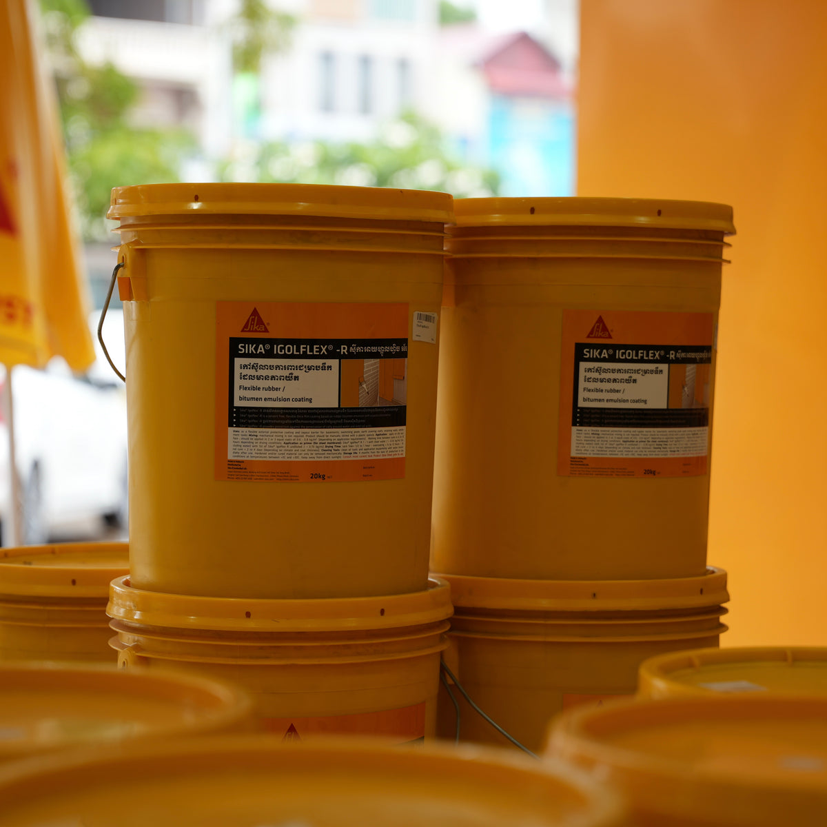 Two yellow buckets with Sika labels on a blurred background