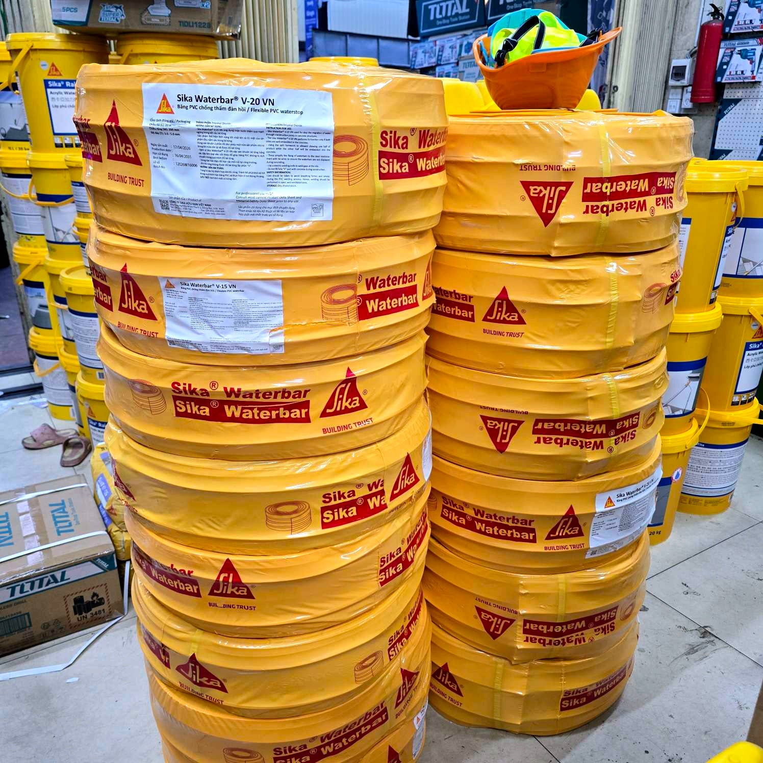 Stacks of yellow Sika Waterbar barrels in a warehouse setting.
