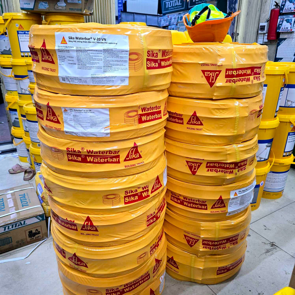 Stacks of yellow Sika Waterbar barrels in a warehouse setting.