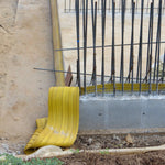 Yellow conduit pipe against a concrete wall with rebar