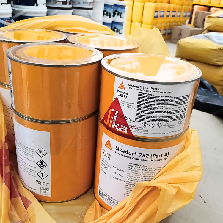 Two large orange Sika containers with labels on a warehouse floor.