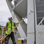 Person painting a large outdoor structure with a roller