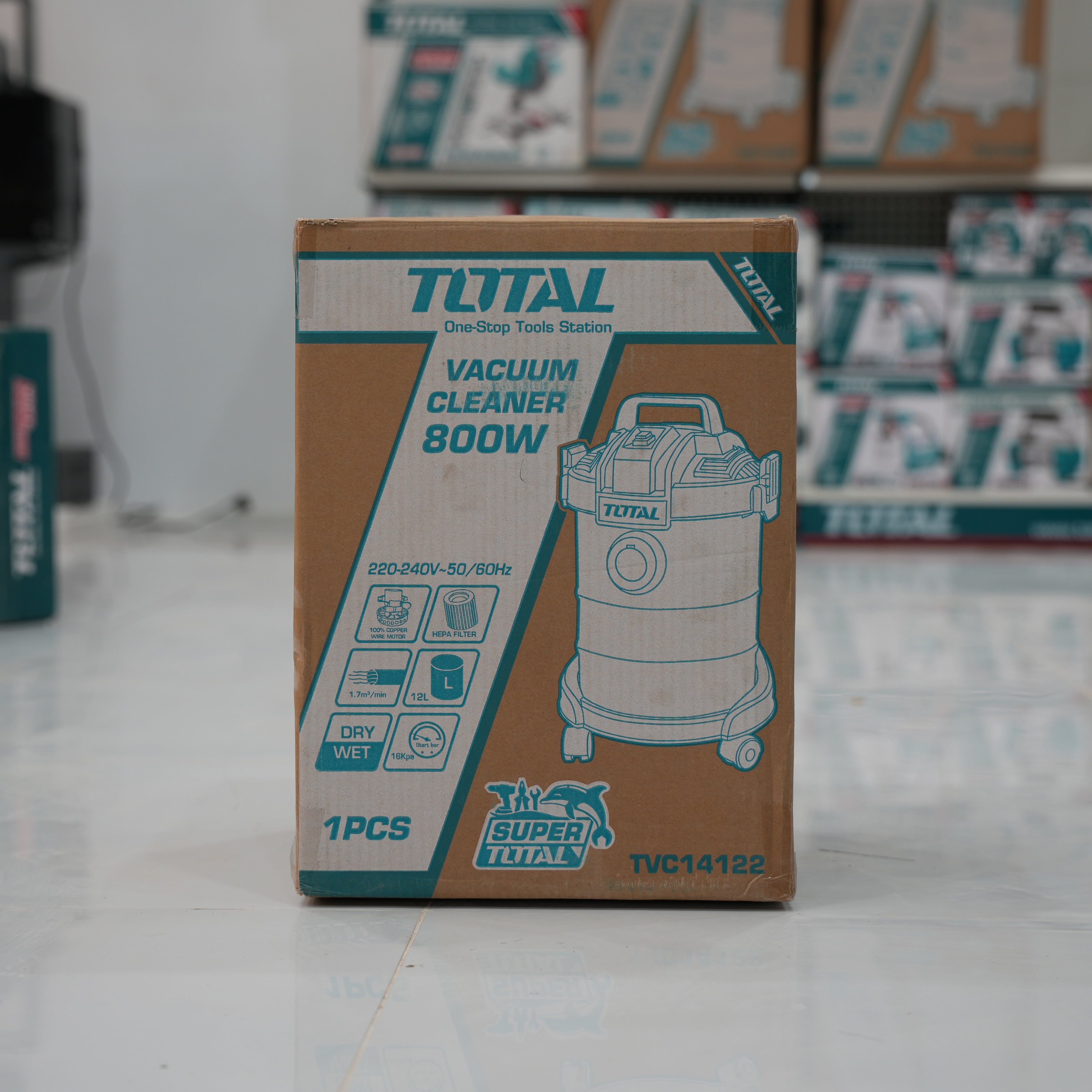 Total brand vacuum cleaner box on a store floor with blurred shelves in the background